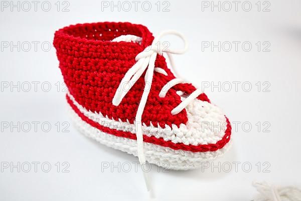 Baby shoes or crochet shoes in red and white isolated against a white background,