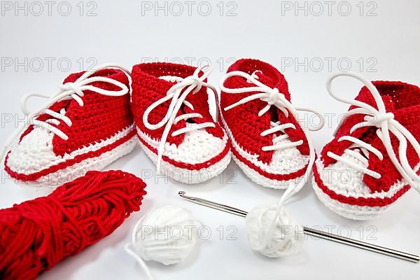 Baby shoes or crochet shoes in red and white isolated against a white background,