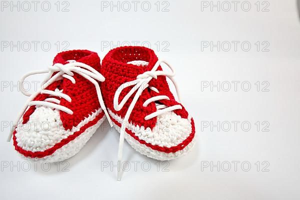 Baby shoes or crochet shoes in red and white isolated against a white background,