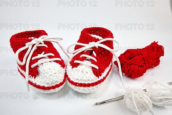 Baby shoes or crochet shoes in red and white isolated against a white background,