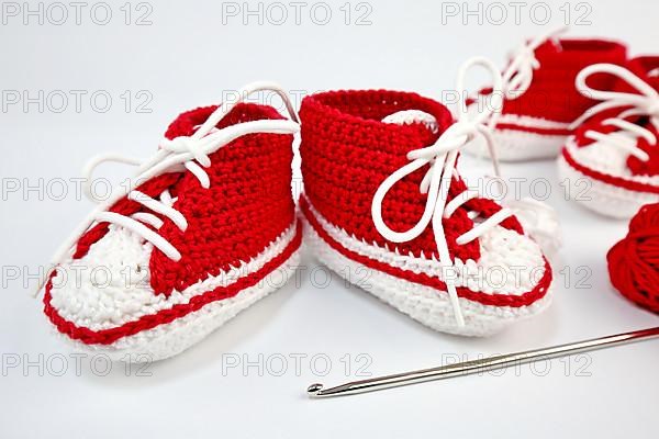 Baby shoes or crochet shoes in red and white isolated against a white background,