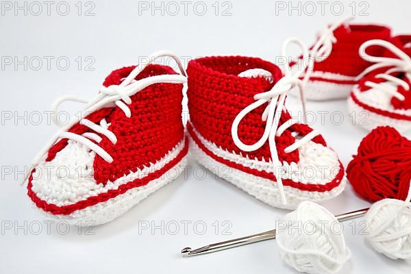 Baby shoes or crochet shoes in red and white isolated against a white background,