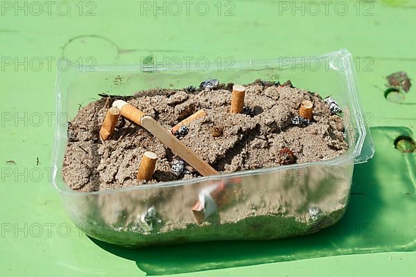 Cigarette butts in a plastic bowl as an ashtray, Germany