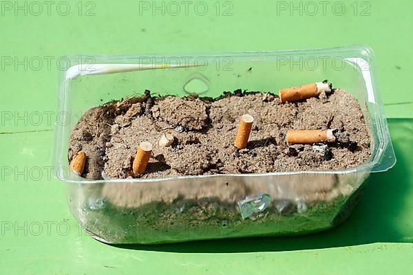 Cigarette butts in a plastic bowl as an ashtray, Germany