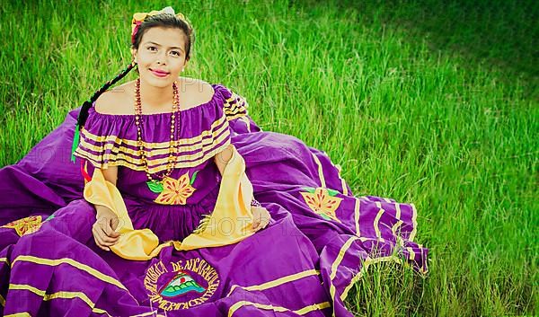 Portrait of Nicaraguan girl in folk costume sitting on the grass, Young Nicaraguan girl in traditional folk costume sitting on the grass in the field