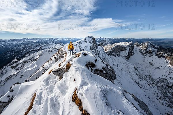 Climbers on a narrow rocky snowy ridge, behind peak crow