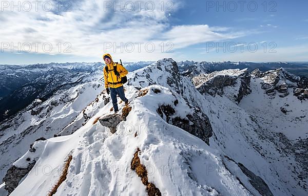 Climbers on a narrow rocky snowy ridge, behind peak crow