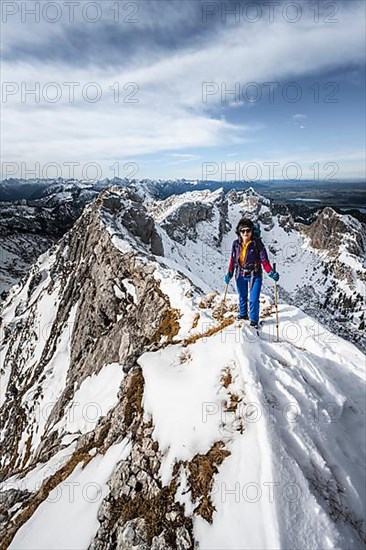 Climber on a rocky snowy ridge, behind peak crow