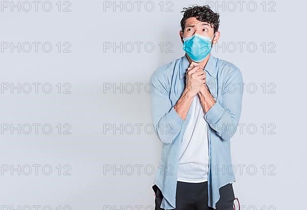 Person with medical mask with hands together begging for a favor or miracle isolated. A young man wearing surgical mask begging for a miracle isolated, man in medical mask asking for a favor