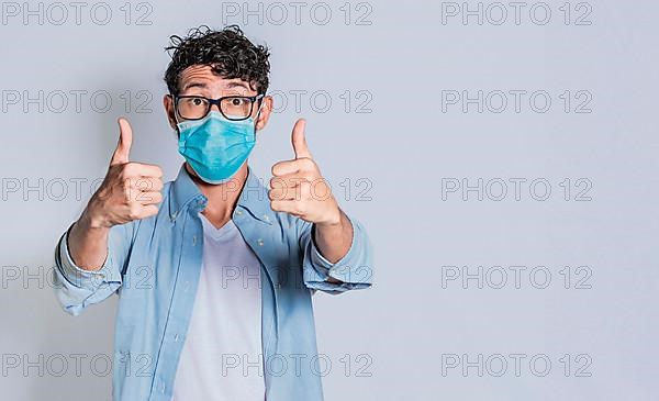 Man wearing medical mask and giving thumbs up, Isolated person wearing medical mask giving thumbs up
