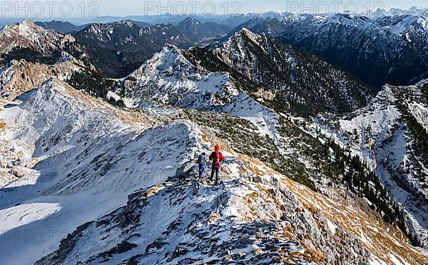 Two mountaineers on the narrow rocky snowy ridge of the Ammergauer Hochplatte, view towards Loesertaljoch