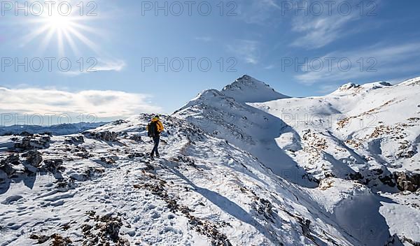 Climbers on the rocky snowy ridge of the Ammergauer Hochplatte, view of snowy summit of the Ammergauer Hochplatte