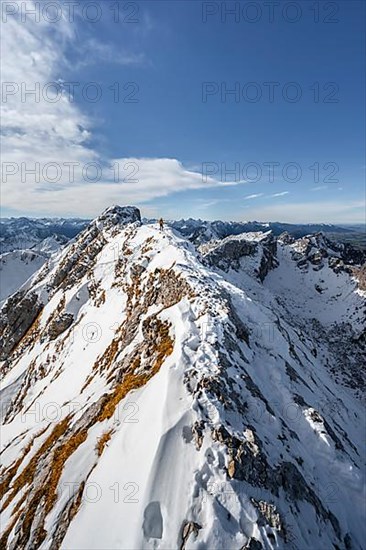 Climbers on a narrow rocky snowy ridge, behind peak crow