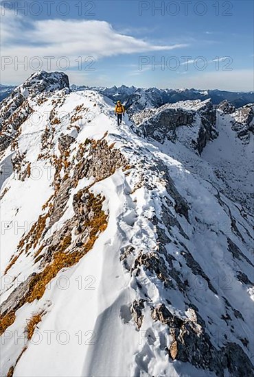 Climbers on a narrow rocky snowy ridge, behind peak crow