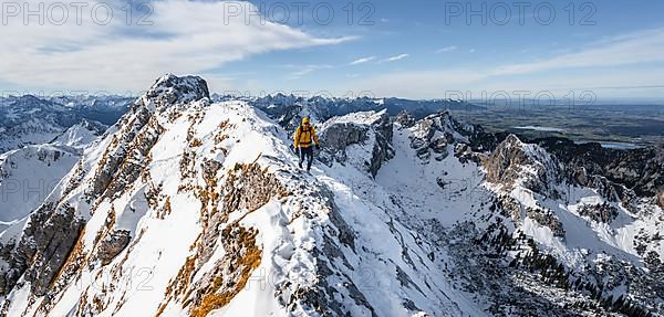 Climbers on a narrow rocky snowy ridge, behind peak crow