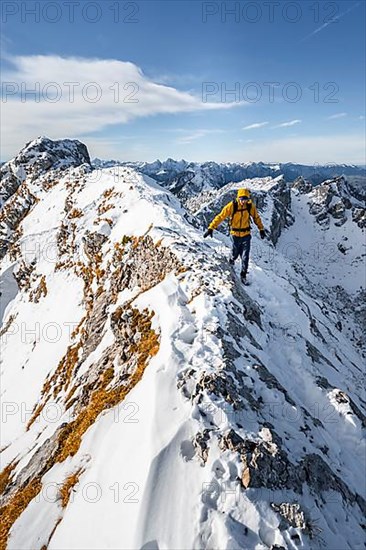 Climbers on a narrow rocky snowy ridge, behind peak crow