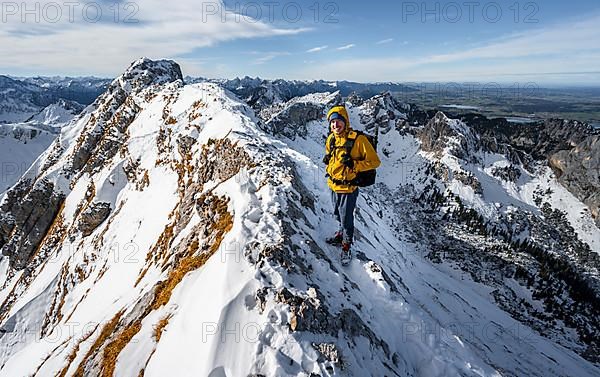 Climbers on a narrow rocky snowy ridge, behind peak crow