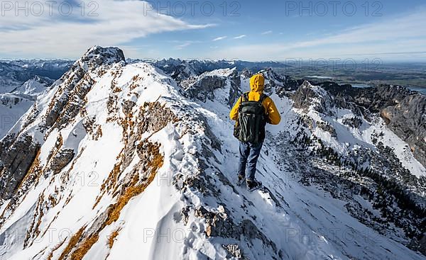 Climbers on a narrow rocky snowy ridge, behind peak crow