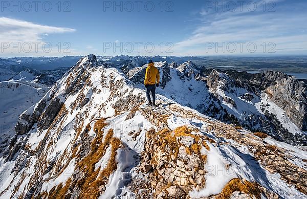 Climbers on a narrow rocky snowy ridge, behind peak crow