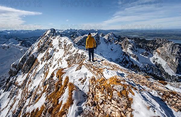 Climbers on a narrow rocky snowy ridge, behind peak crow