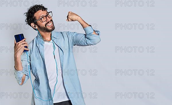 Happy handsome man with headphones holding a cell phone and celebrating, Happy person using his smartphone and celebrating victory isolated