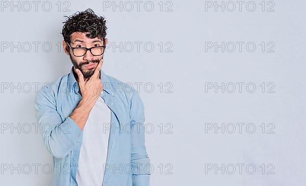 Handsome man rubbing his beard with a doubtful expression, Person rubbing his chin with a doubtful expression. handsome bearded man with doubt expression isolated