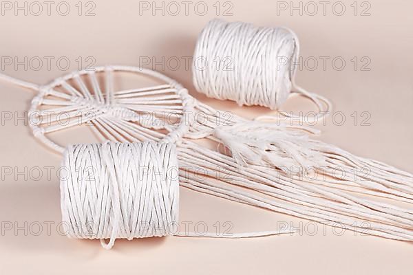 Cream white cotton macrame cord used for DIY decoration object on beige background,