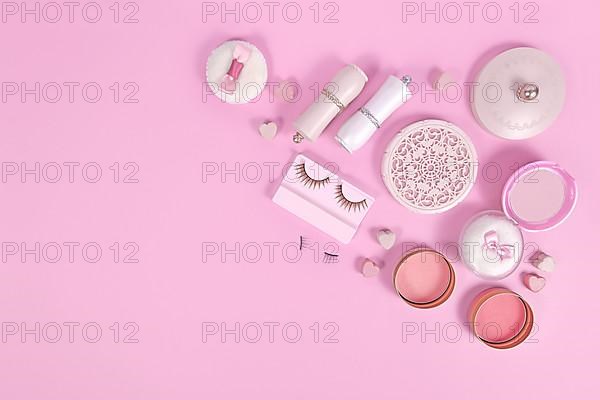 Cute pink makeup beauty products like brushes, powder or lipstick on side of pastel pink background with empty copy space