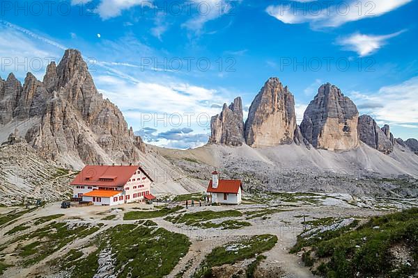 View of mountain hut Dreizinnenhuette and chapel with rock massif Paternkofel and mountain range drei Zinnen, panorama