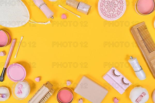 Various makeup beauty products like brushes, powder or lipstick surrounding yellow background with empty copy space