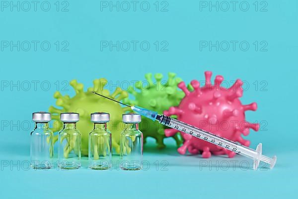 4 vaccine vials with syringes and corona virus models in background,