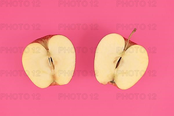 Apple cut into half on pink background,