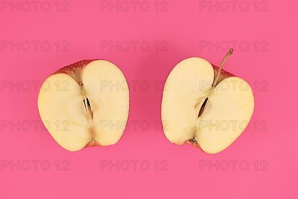 Apple cut into half on pink background,