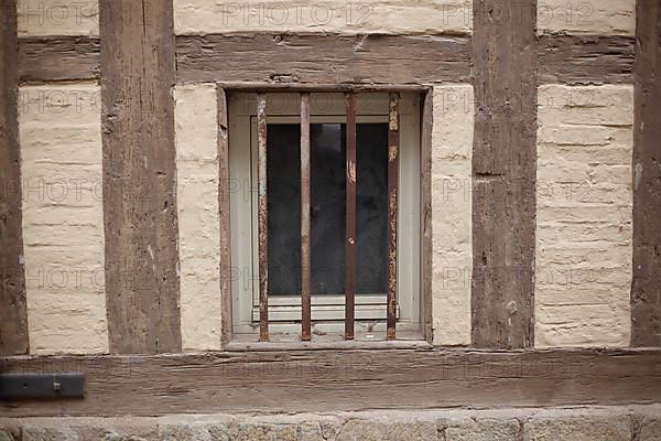 Old window with window grille on a brown house wall with half-timbered beams, Quedlinburg