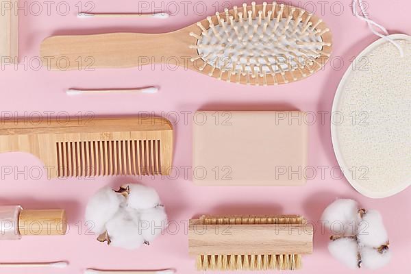 Eco friendly wooden beauty and hygiene products like comb and soap on pink background,