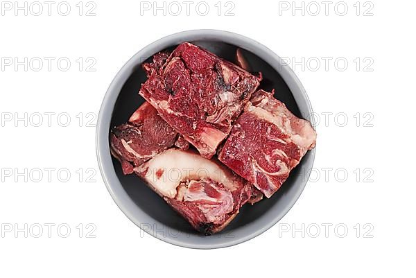 Dog bowl with big red chunks of meat with fat used for raw biologically appropriate feeding on white background,