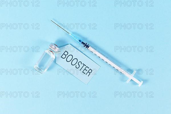 Concept for Corona virus booster vaccination with vial and syringe on blue background,