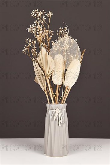 Natural bouquet wit gray vase with dried flowers and leaves like palm leaf, skeleton leaf