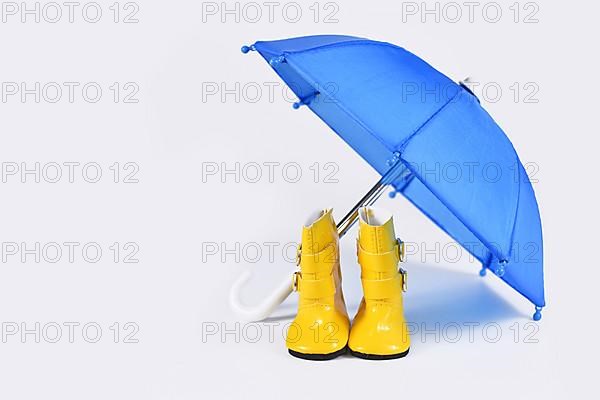 Rain concept with blue umbrella and yellow rubber boots,
