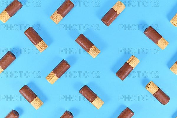 Chocolate glazed waver rolls sweets arranged on blue background,