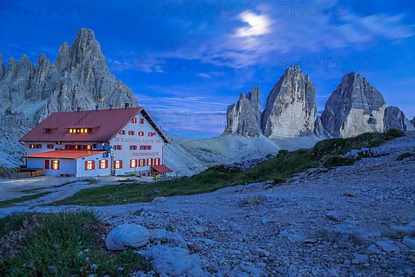 Mountain hut Dreizinnenhuette with rock massif Paternkofel and mountains three peaks at night, Dolomites