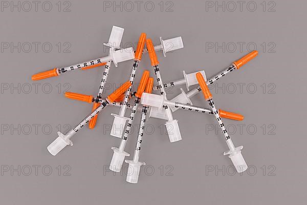 Bunch of small 0, 3 ml U100 insulin syringes used to treat diabetes disease on gray background