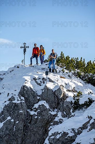 Mountaineer next to summit cross, hiking to Weitalpspitz in the Ammergau Alps