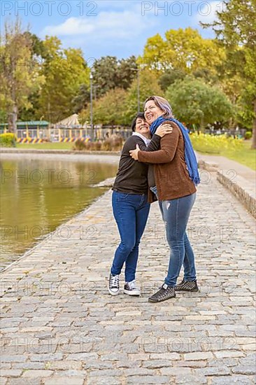 Lesbian couple hugging in a park laughing,