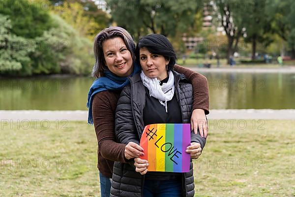 Love. Cheerful queer couple holding a message supporting the LGBT community,