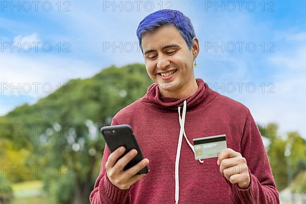 Latin gay man using credit card to make online payment on smartphone. mixed-race man using cellphone for shopping online. Guy using smart phone to check credit card transactions from app. Copy space,