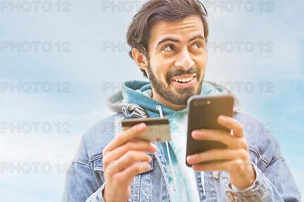 Latin man using credit card to make online payment on smartphone. mixed-race man using cellphone for shopping online. Guy using smart phone to check credit card transactions from app. Copy space,