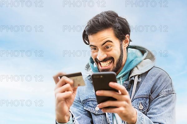 Latin man using credit card to make online payment on smartphone. mixed-race man using cellphone for shopping online. Guy using smart phone to check credit card transactions from app. Copy space,