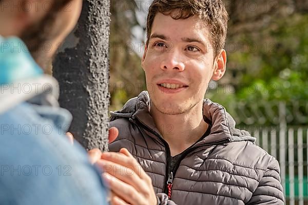 Latin gay couple having fun at a park looking at each other,