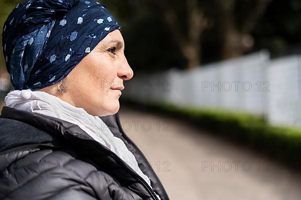 Portrait of a Latin woman undergoing cancer treatment with her head covered by a scarf with an expression of strength,